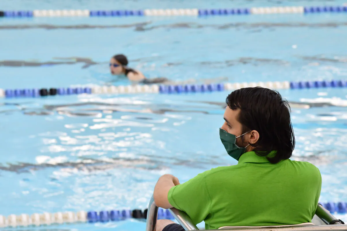 A lifeguard wearing a protective face mask as a precautionary measure against COVID-19 keeps watch over swimmers in the pool at Kensington Leisure Centre in west London on July 25, 2020. (Justin Talllis/AFP via Getty Images)