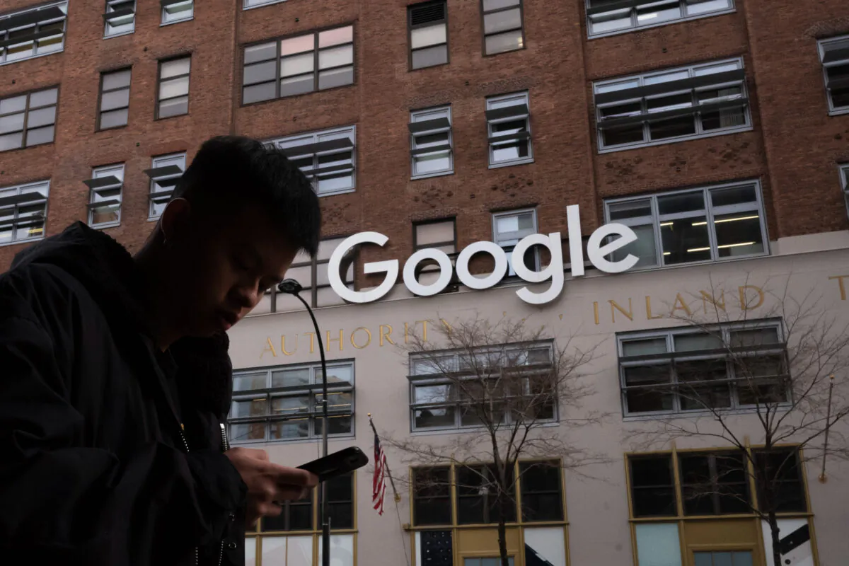 A man using a mobile phone walks past Google offices in New York on Dec. 17, 2018. (Mark Lennihan/AP Photo)