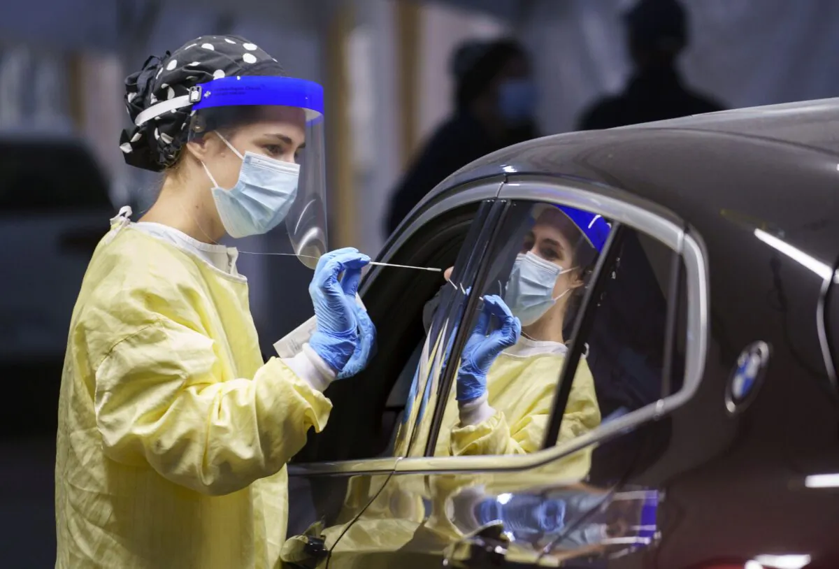 A nurse performs a test on a person at a drive-in COVID-19 clinic in Montreal on Oct. 21, 2020. (The Canadian Press/Paul Chiasson)
