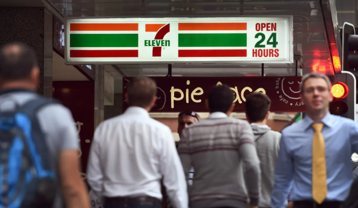 People walk past a 7-Eleven convenience store in Sydney's central business district following allegations that franchises systematically underpaid workers. 
(William West/AFP via Getty Images)