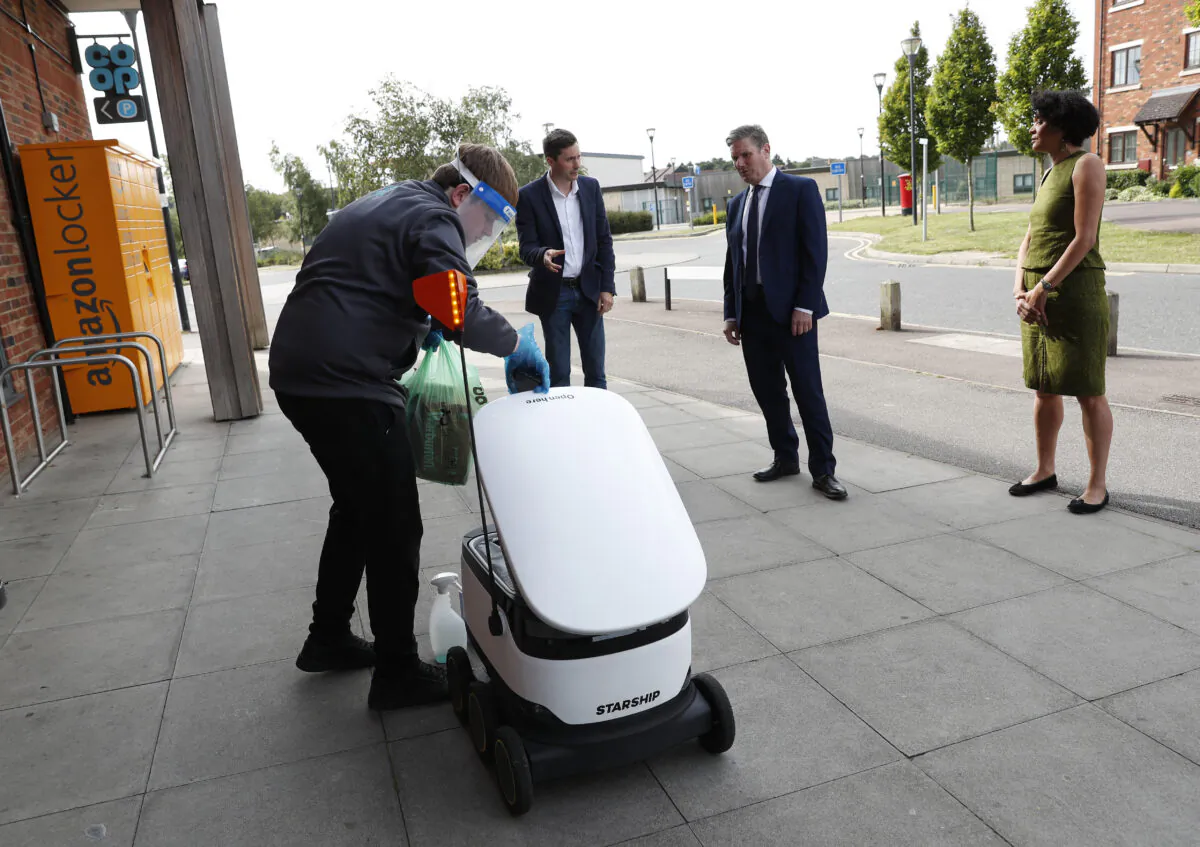 The Labor Leader Keir Starmer, the Shadow Minister for Science, Research and Digital Chi Onwurah, and  Starship Technologies' VP of Marketing Henry Harris-Burlan watch a Co-op supermarket worker load groceries into a Starship delivery robot on July 23, 2020 in Milton Keynes, England. (Darren Staples/Getty Images)