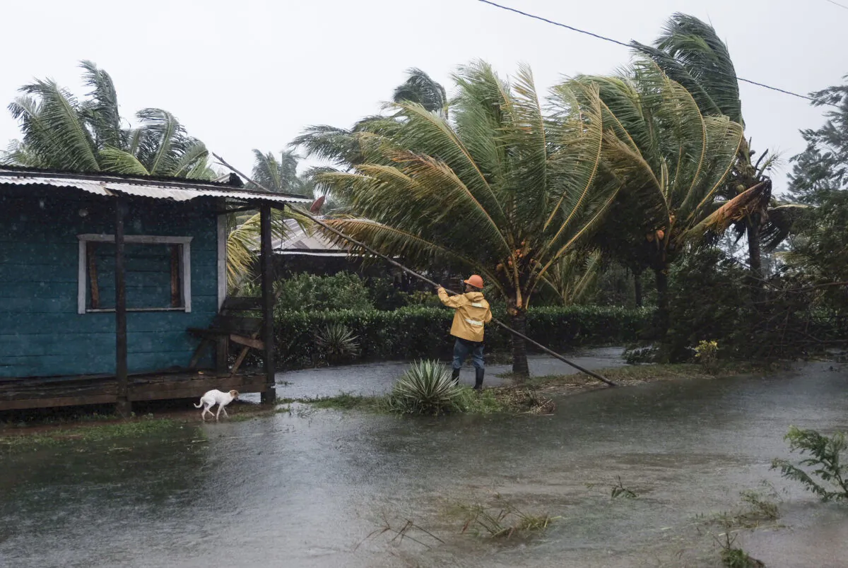 A man fixes the roof of a home surrounded by floodwaters brought on by Hurricane Eta in Wawa, Nicaragua, on Nov. 3, 2020. (Carlos Herrera/AP Photo)