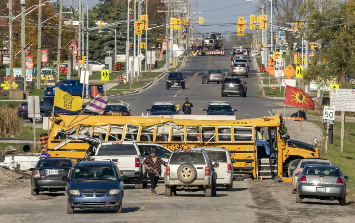Six Nations protesters gather by a destroyed school bus blocking Argyle Street in Caledonia, Ont., on Oct. 28, 2020. (The Canadian Press/Frank Gunn)