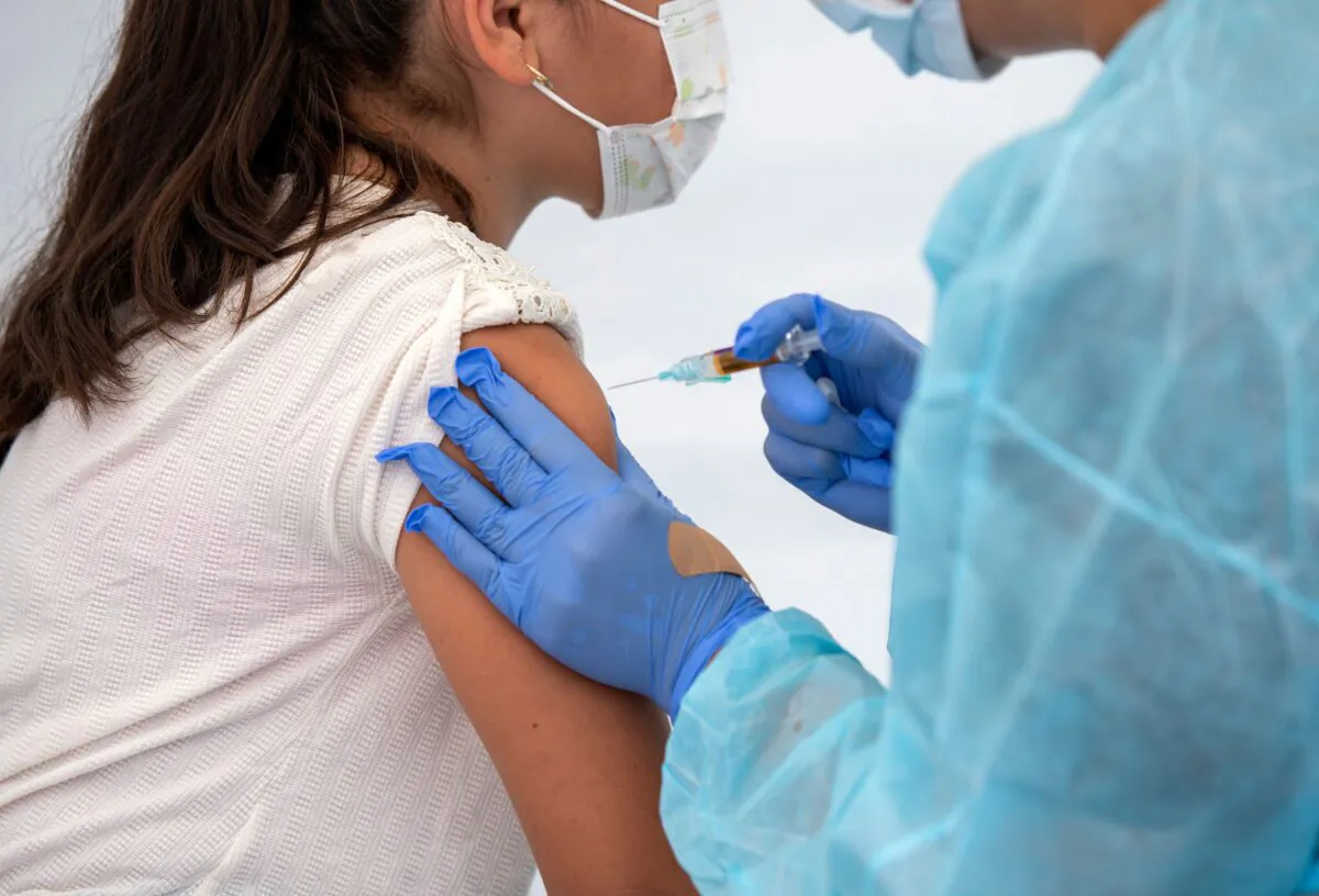A health worker vaccinates a student during a community drive-up clinic in Los Angeles on Aug. 12, 2020. (Valerie Macon/AFP via Getty Images)