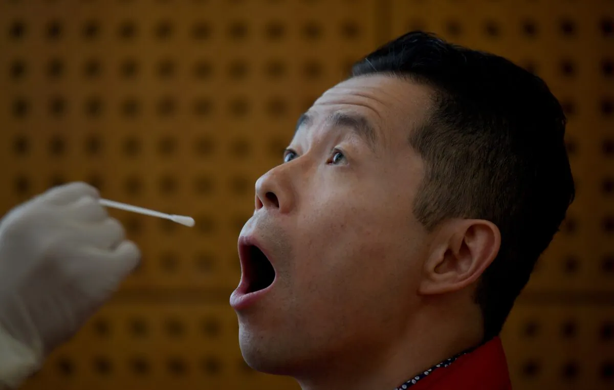 A journalist undergoes a swab test for COVID-19, part of health requirements for media workers covering a government event in Beijing on Oct. 22, 2020. (NOEL CELIS/AFP via Getty Images)