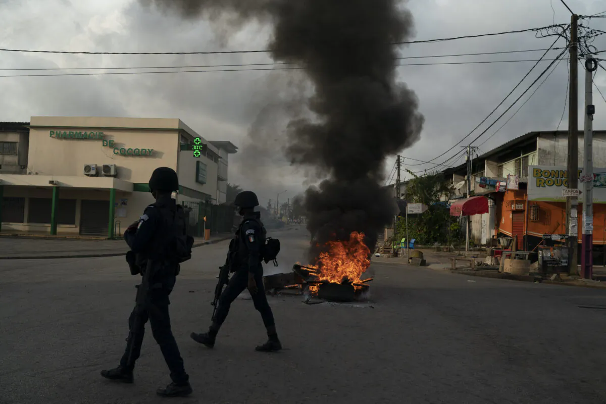 Policemen walk past a burning barricade during a protest after the security forces blocked the access to the house of the former president Henri Konan Bedie, in Abidjan, Ivory Coast on Nov. 3, 2020. (Leo Correa/AP Photo)
