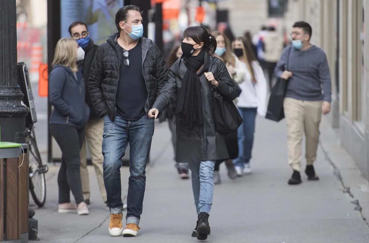 People wearing face masks walk along a street in Montreal on Oct. 18, 2020. (The Canadian Press/Graham Hughes)