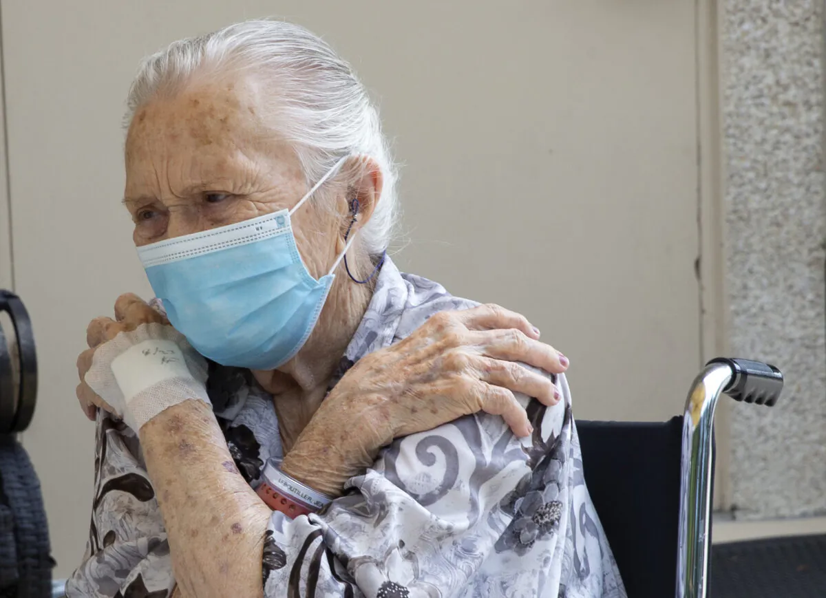 Jean LeBoutillier, a resident at the Life Care Center of Kirkland, says goodbye to her daughter Laurie Callahan and son-in-law, Kevin Callahan  after their visit at the Life Care Center of Kirkland in Kirkland, Wash. on Aug. 24, 2020. (Karen Ducey/Getty Images)