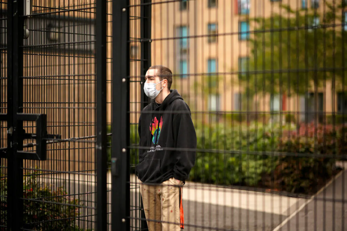 Students who are self-isolating stand behind the security fencing of their accommodation as they are interviewed by a television crew while self-isolating in Manchester, England on Sept. 28, 2020. (Christopher Furlong/Getty Images)