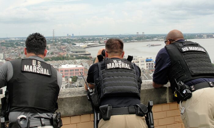 U.S. Marshals stand on a building as they look out toward the city in a file photo. (Illustration - Elliott Cowand Jr/Shutterstock)