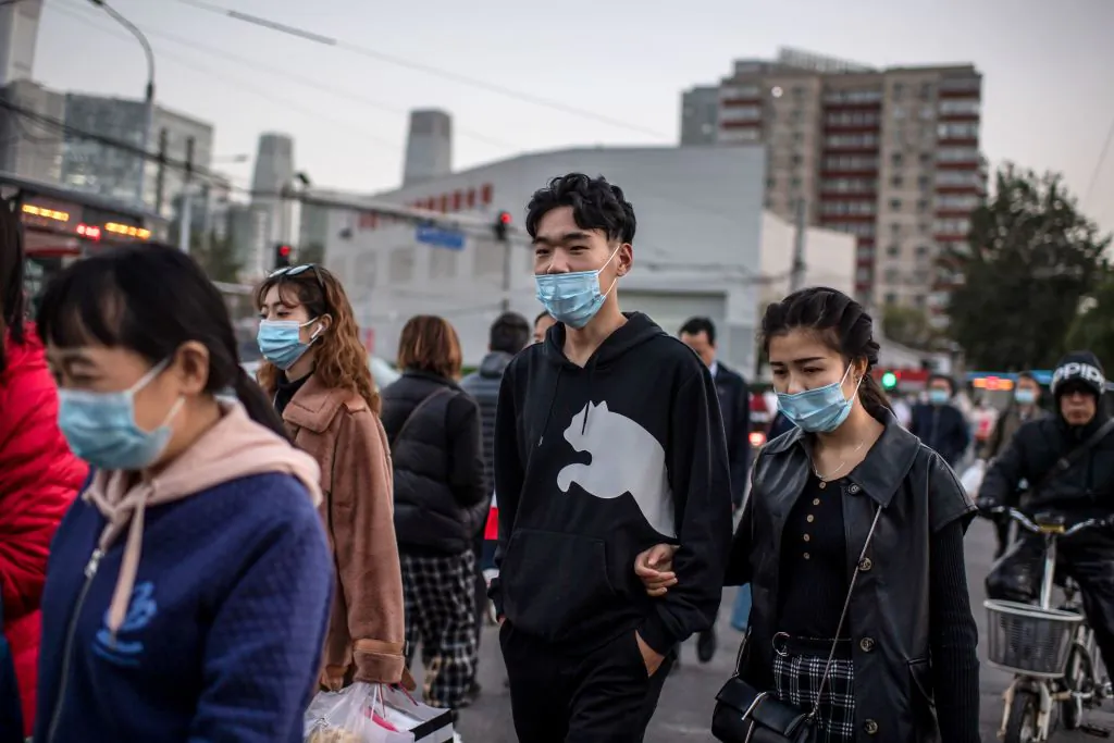 People cross a street during rush hour in Beijing on Oct. 21, 2020. (Nicolas Asfouri/AFP via Getty Images)
