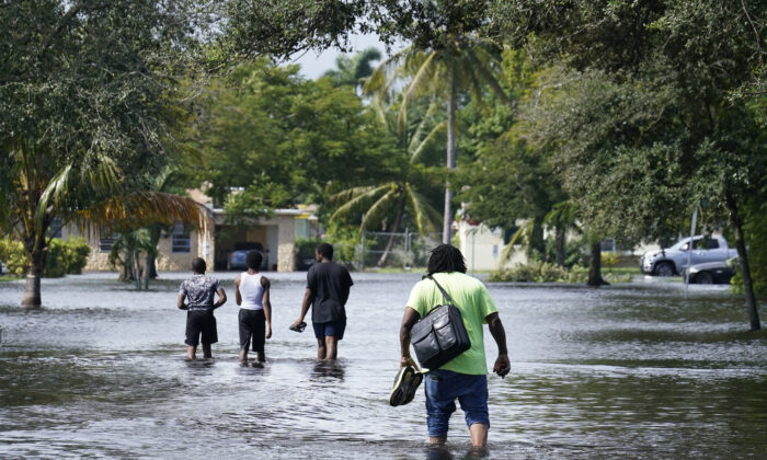 Residents walk a flooded street to reach their homes, Nov. 9, 2020, in Fort Lauderdale, Fla. Tropical Storm Eta caused severe flooding in South Florida in areas already saturated from previous downpours.  (AP Photo/Marta Lavandier)