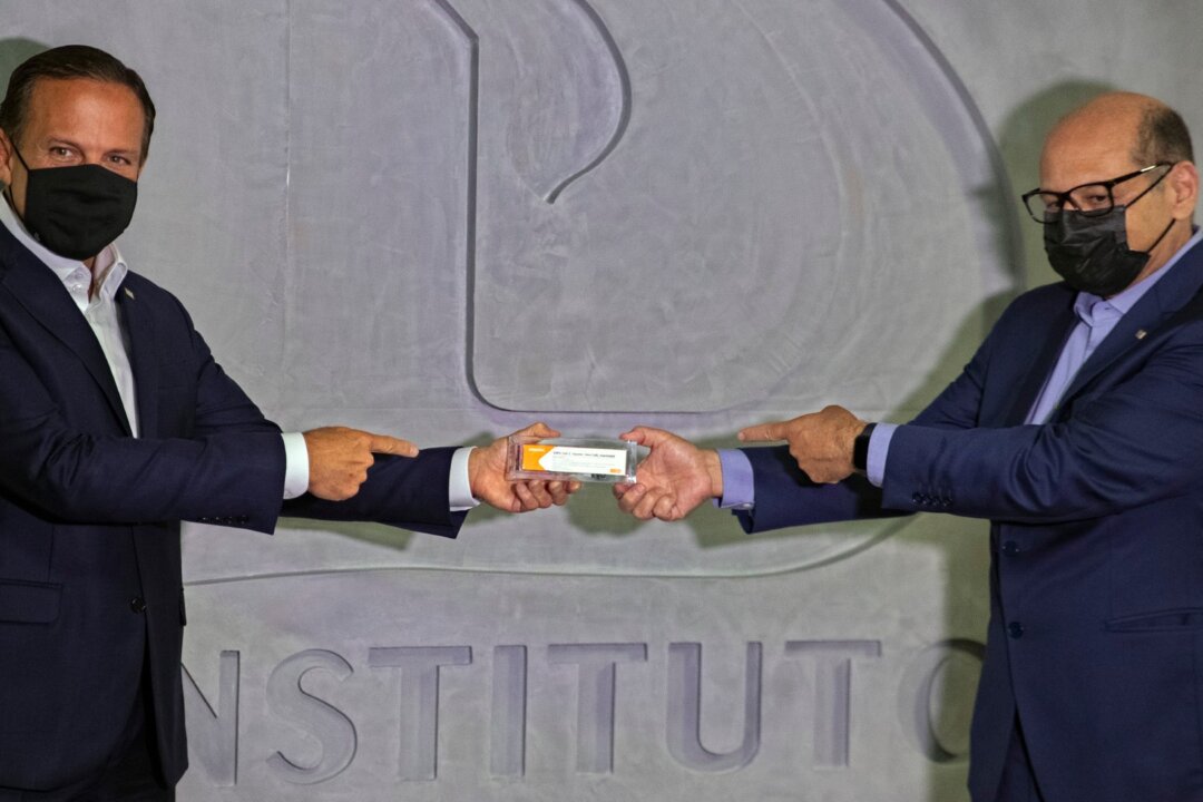 Sao Paulo Governor Joao Doria (L) and Butantan Institute Director Dimas Covas (R) hold up a box of an experimental COVID-19 vaccine during a press conference in Sao Paulo, Brazil, on Nov. 9, 2020. (Andre Penner/AP Photo)