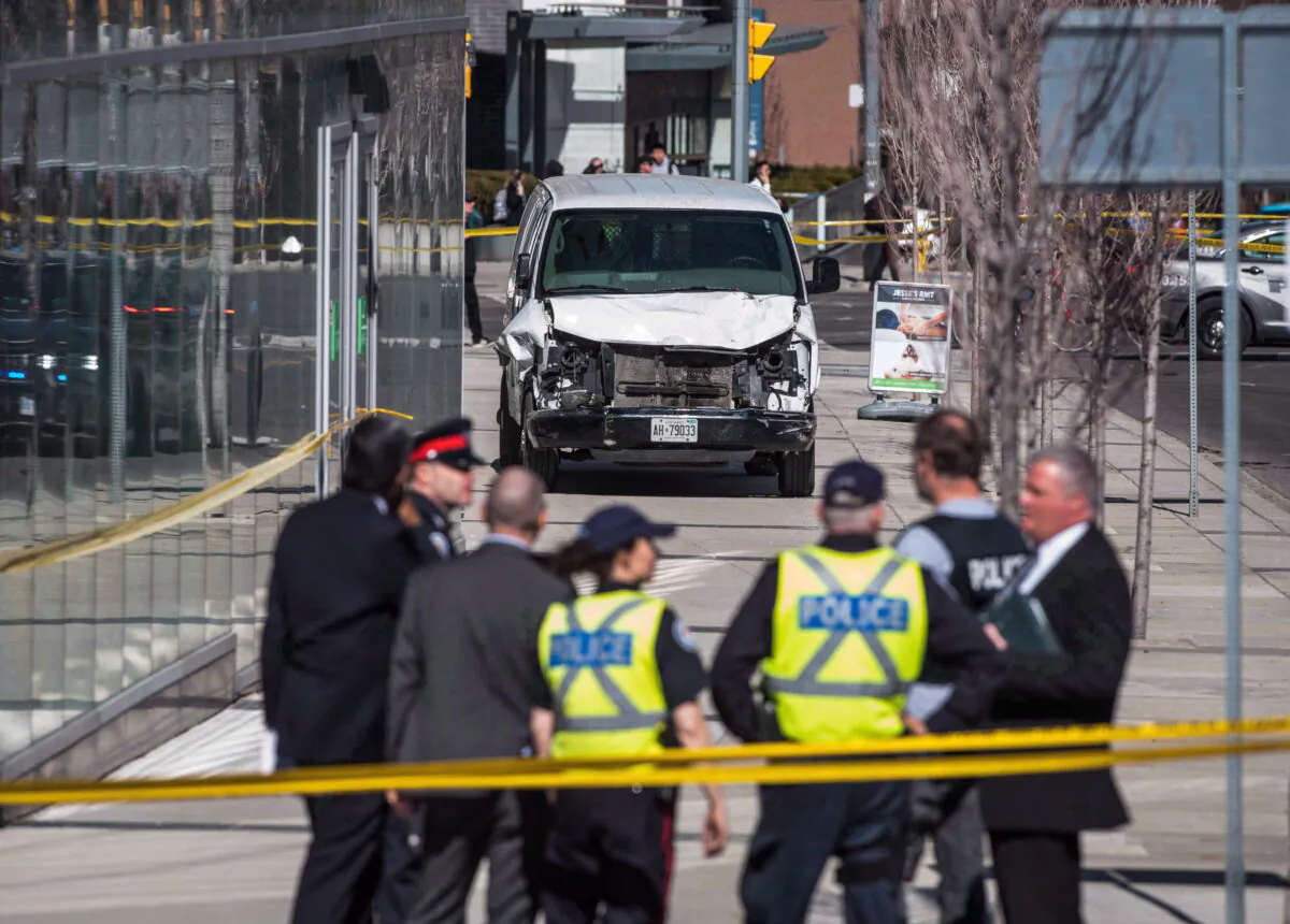 Police are seen near a damaged van in Toronto after a van mounted a sidewalk crashing into a number of pedestrians on Monday, April 23, 2018. (Aaron Vincent Elkaim/The Canadian Press)