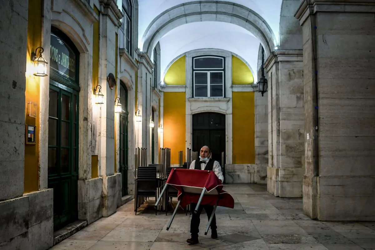 A waiter carries a table just as he prepares to close a restaurant in downtown Lisbon, Portugal, on Nov. 9, 2020. (Patricia De Melo Moreira/AFP/Getty Images)