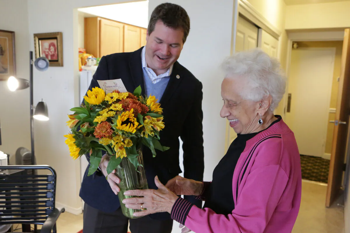 Random Acts of Flowers CEO Larsen Jay delivers the nonprofit's 100,000th bouquet to Joan Taylor, a senior in Chicago Nov. 12, 2015. (Jean Marc Giboux/AP Images for FTD and ProFlowers.)