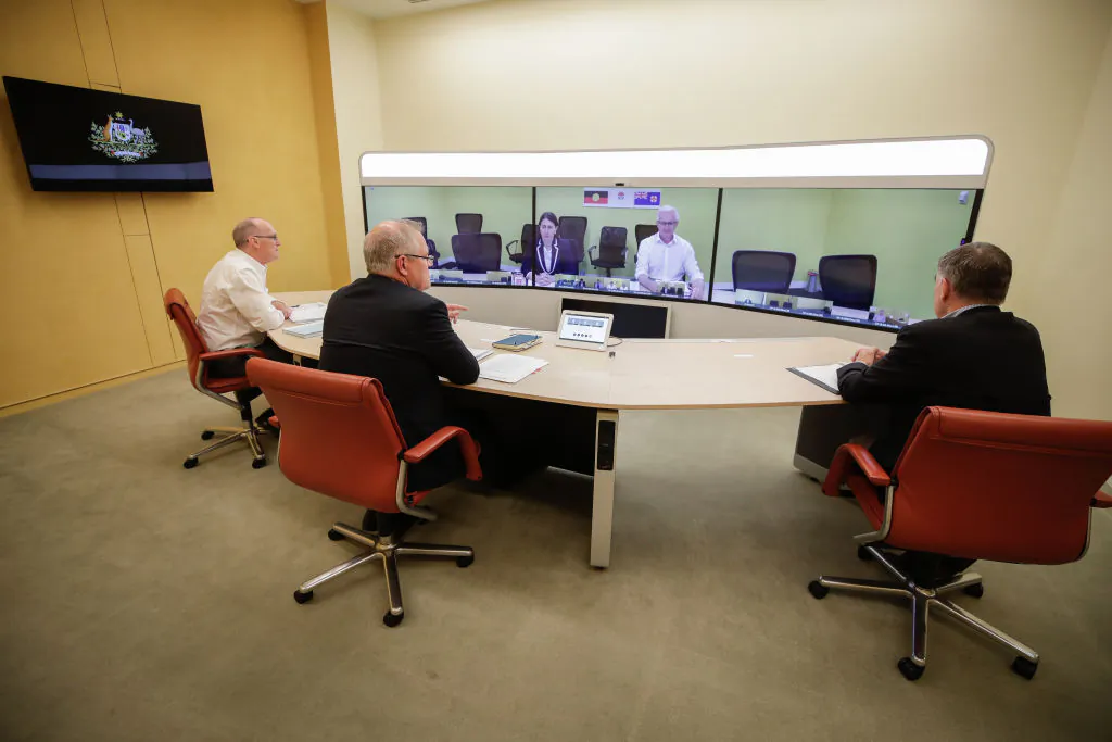  L-R foreground: Secretary of the Department of Prime Minister and Cabinet, Phil Gaetjens, Australian Prime Minister Scott Morrison and Chief Medical Officer Professor Brendan Murphy, speak with NSW Premier Gladys Berejiklian (on screen) during a National Cabinet meeting to discuss COVID-19, from the telepresence room of Parliament House on 22 March, 2020 in Canberra, Australia.  (Alex Ellinghausen - Pool/Getty Images)