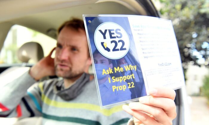 Uber driver Sergei Fyodorov holds a sign in support of Proposition 22 in Oakland, Calif., on Oct. 9, 2020. (Josh Edelson/AFP via Getty Images)
