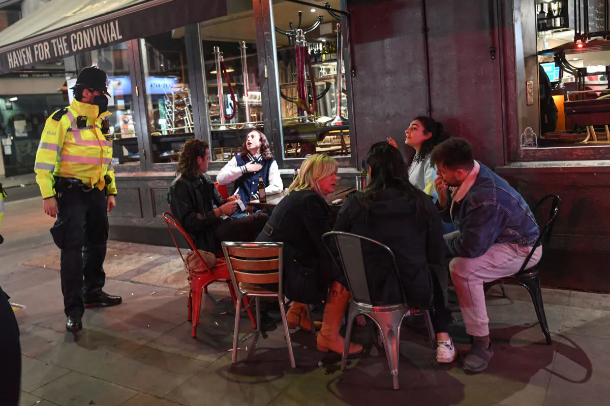 A police officer speaks to people sitting outside a pub in Soho in London, England, on Sept. 24, 2020. (Peter Summers/Getty Images)