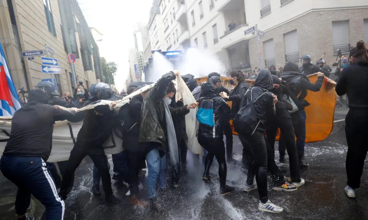 Police officers use a water cannon against  counter-demonstrators standing on a road to stop a protest against the government's restrictions, amid the CCP virus disease outbreak, in Frankfurt, Germany, on Nov. 14, 2020. (Kai Pfaffenbach/Reuters)