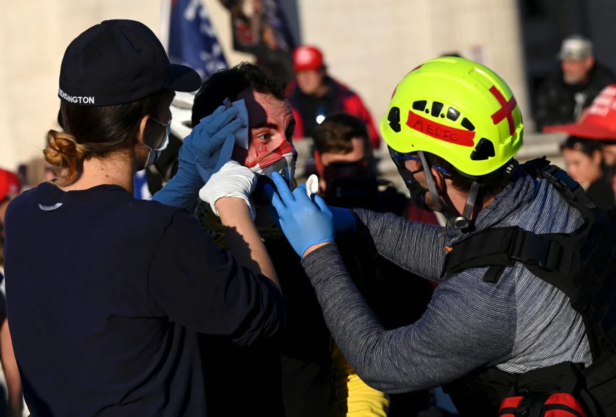 An injured supporter of President Donald Trump is helped after being assaulted by two men described by journalists as Antifa members, during a rally in Washington, on Nov. 14, 2020. (Andrew Caballero-Reynolds/AFP via Getty Images)