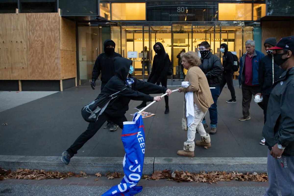 A man dressed in black tries to take a Trump 2020 flag from an elderly President Donald Trump supporter in Washington on Nov. 14, 2020. (Roberto Schmidt/AFP via Getty Images)