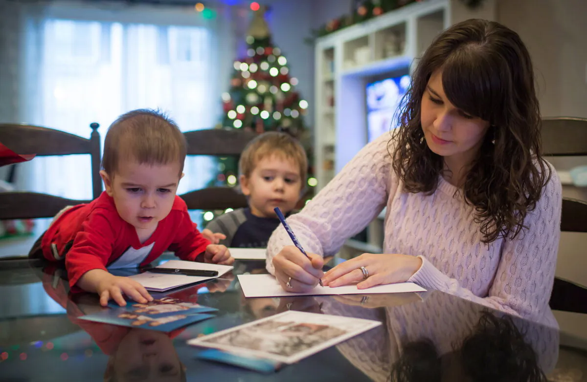 Carolyn Bechard writes in a Christmas card as her sons Asher, left, 1, and Noah, 3, sit with her at their home in Surrey, B.C., Canada on Dec. 11, 2014. (Darryl Dyck/The Canadian Press)