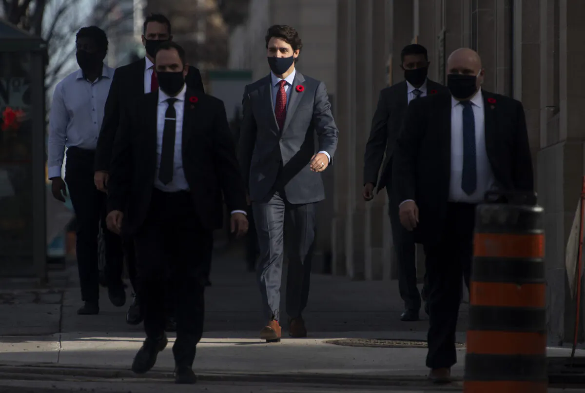Prime Minister Justin Trudeau and his security detail walk past a construction worker as they make their way to a news conference in Ottawa,  on Nov. 10, 2020. (Adrian Wyld/The Canadian Press)