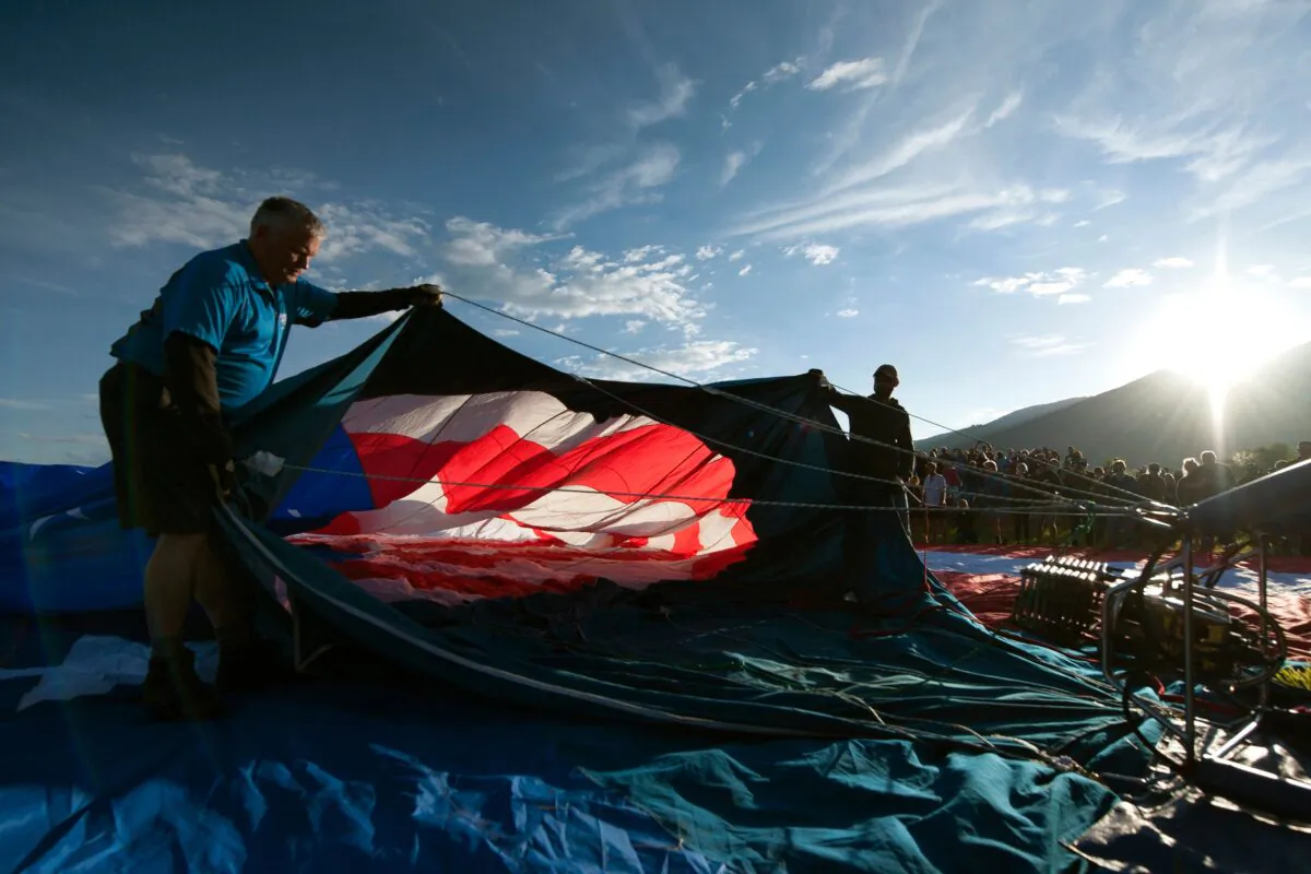 Crew members hold open the envelope of the balloon Dee IV as they fill it with air from high-powered fans at the start of the 38th annual Steamboat Springs Hot Air Balloon Festival in Steamboat Springs, Colorado on July 13, 2019. Dee IV is one of two balloons that launches at the start of the rodeo each year during the recital of the Pledge of Allegiance by spectators. (Jason Connolly / AFP via Getty Images)