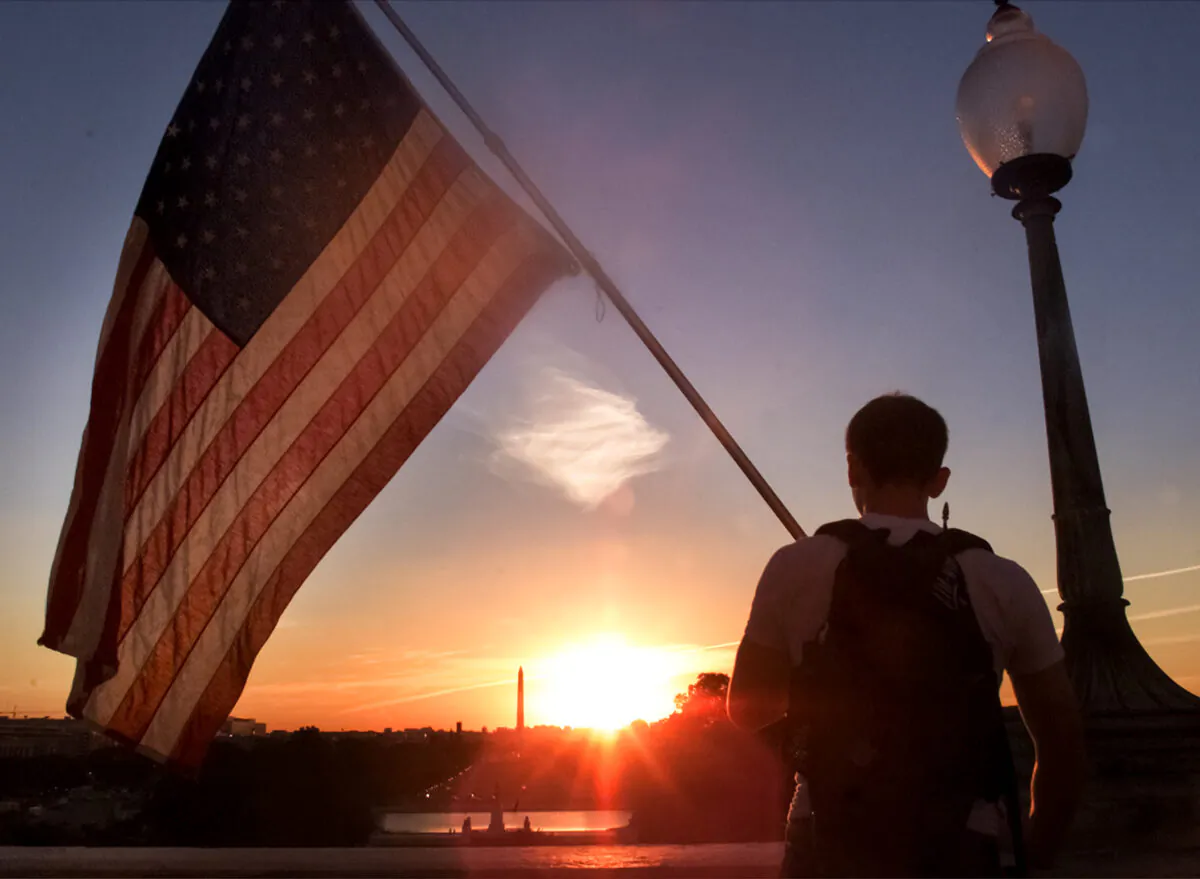 With the sun setting behind the Washington Monument, a person holds an American Flag up on the west side of the U.S. Capitol building on Sept. 12, 2001, a day after terrorist attacks in Washington and New York killed thousands. (Mark Wilson/Getty Images)