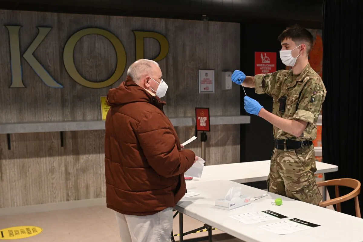 A British Army soldier hands a member of the public a swab and provides information on its use inside Anfield Stadium, in Liverpool, on Nov. 10, 2020 (Oli Scarff/AFP via Getty Images)