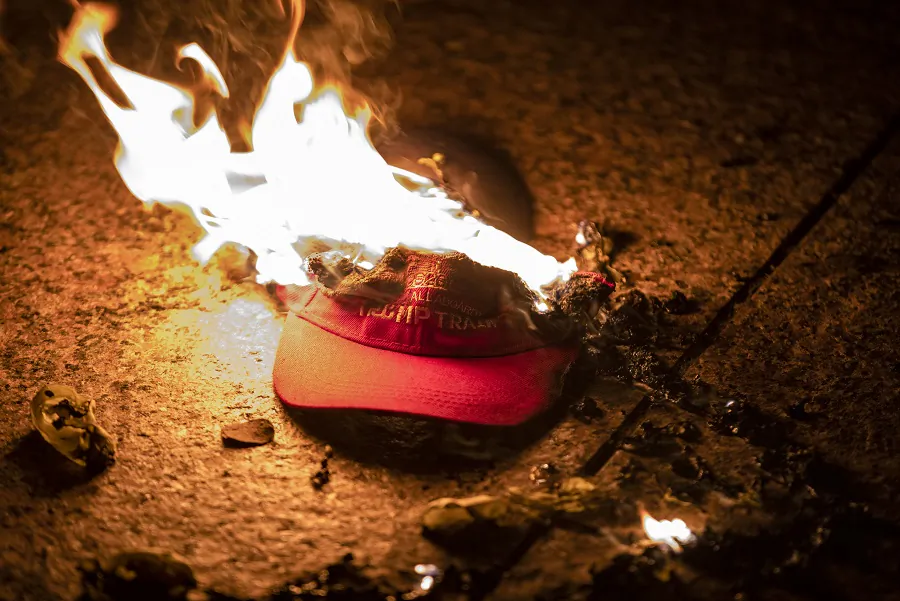 Members of an Antifa group burn a Trump Train hat following the "Million MAGA March" in Washington on Nov. 14, 2020. (Samuel Corum/Getty Images)