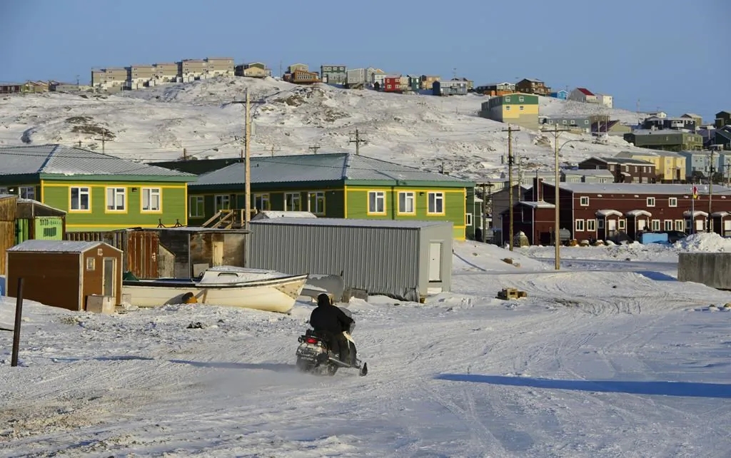 A snowmobiler makes his way along a road in Iqaluit, Nunavut, on March 6, 2019. (The Canadian Press/Sean Kilpatrick)
