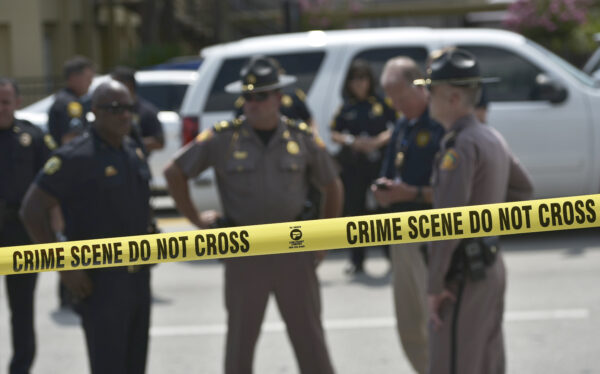 Police stand behind a crime scene tape