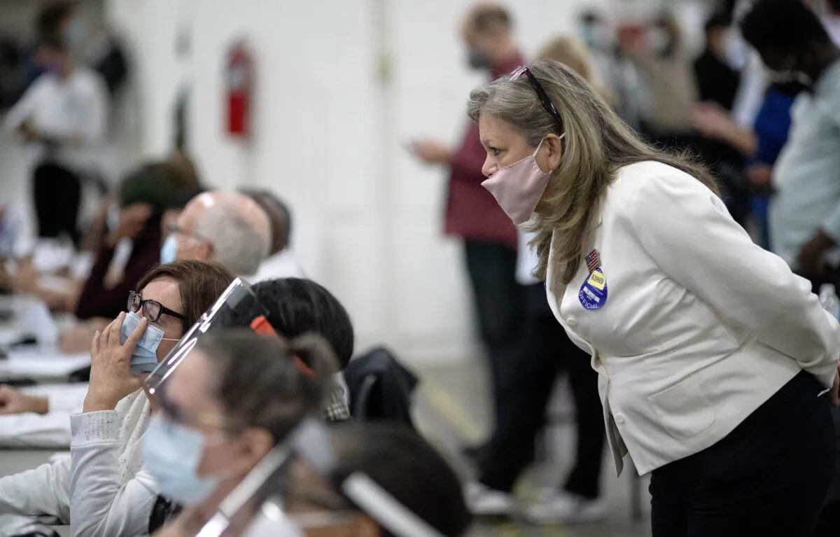 A Republican election challenger at right watches over election inspectors as they examine a ballot as votes are counted into the early morning hours at the central counting board in Detroit, Mich., on Nov. 4, 2020. (David Goldman/AP Photo)