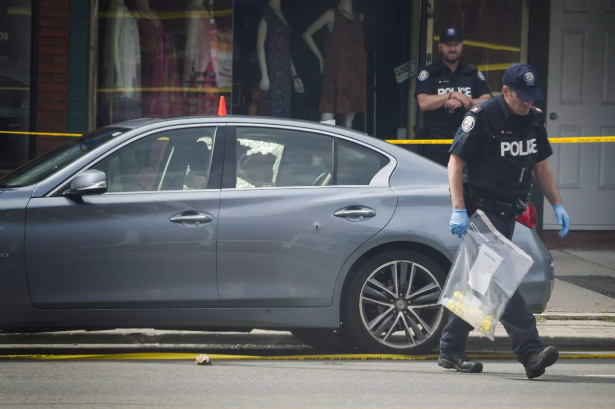 Police investigate a car with a bullet hole at the scene of a shooting in east Toronto, on July 23, 2018. (The Canadian Press/Christopher Katsarov)