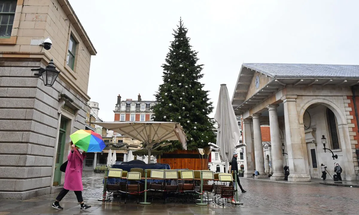 People walk in the rain past a solitary Christmas Tree in a near-deserted Covent Garden in central London, on Nov. 19, 2020,  (Justin Tallis/AFP via Getty Images)