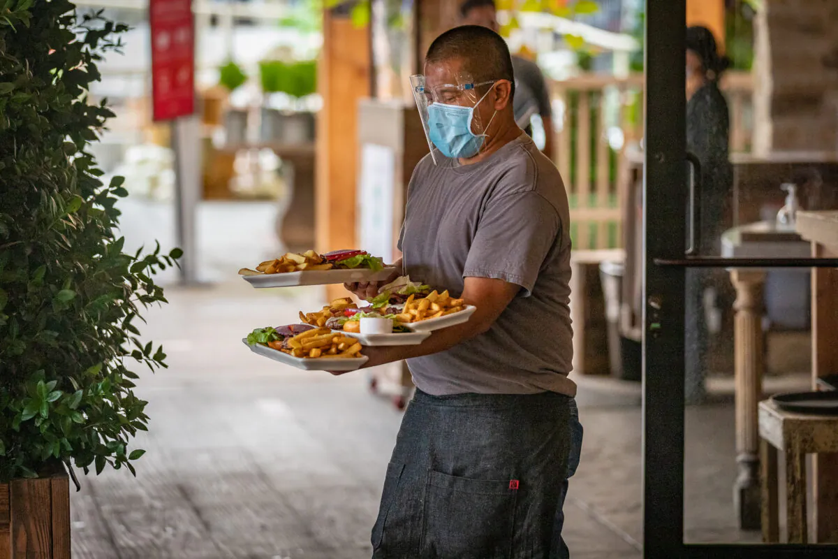 A waiter delivering food to a table at a restaurant in Newport Beach, Calif., on Sept. 9, 2020. (John Fredricks/The Epoch Times)