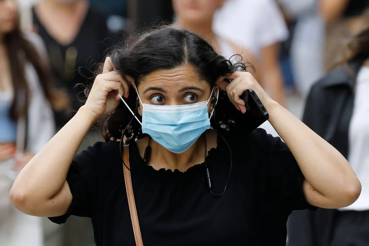 A shopper adjusts her mask on Oxford Street in London on July 24, 2020. (Tolga Akmen/AFP via Getty Images)