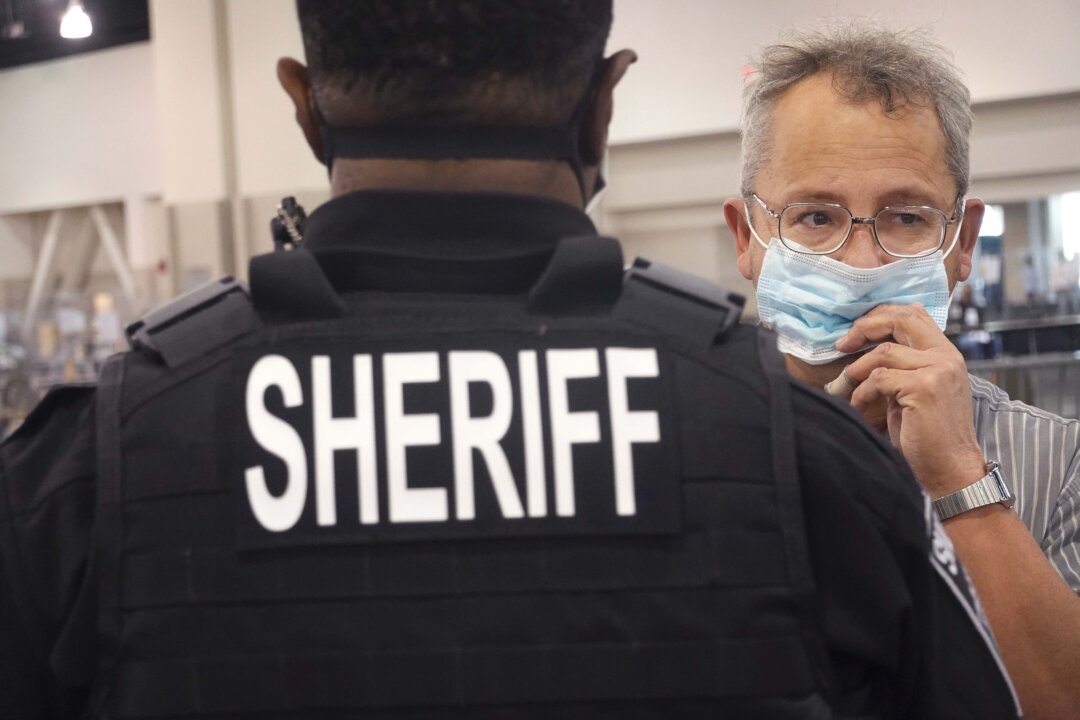 An observer is removed from the hall by police after refusing to properly wear a mask as election officials begin the recount process of ballots from the November 3 election at the Wisconsin Center in Milwaukee on Nov. 20, 2020. (Scott Olson/Getty Images)