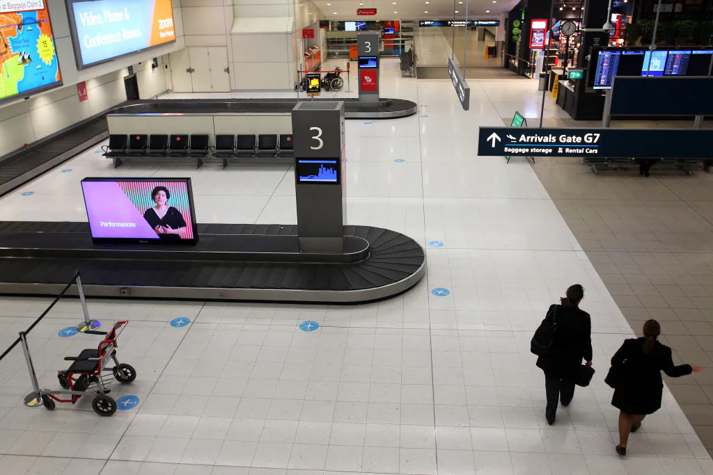 Airline staff walk past empty baggage carousels at the Sydney Domestic Airport Terminal arrivals area in Sydney, Australia on Aug. 7, 2020. (Lisa Maree Williams/Getty Images)