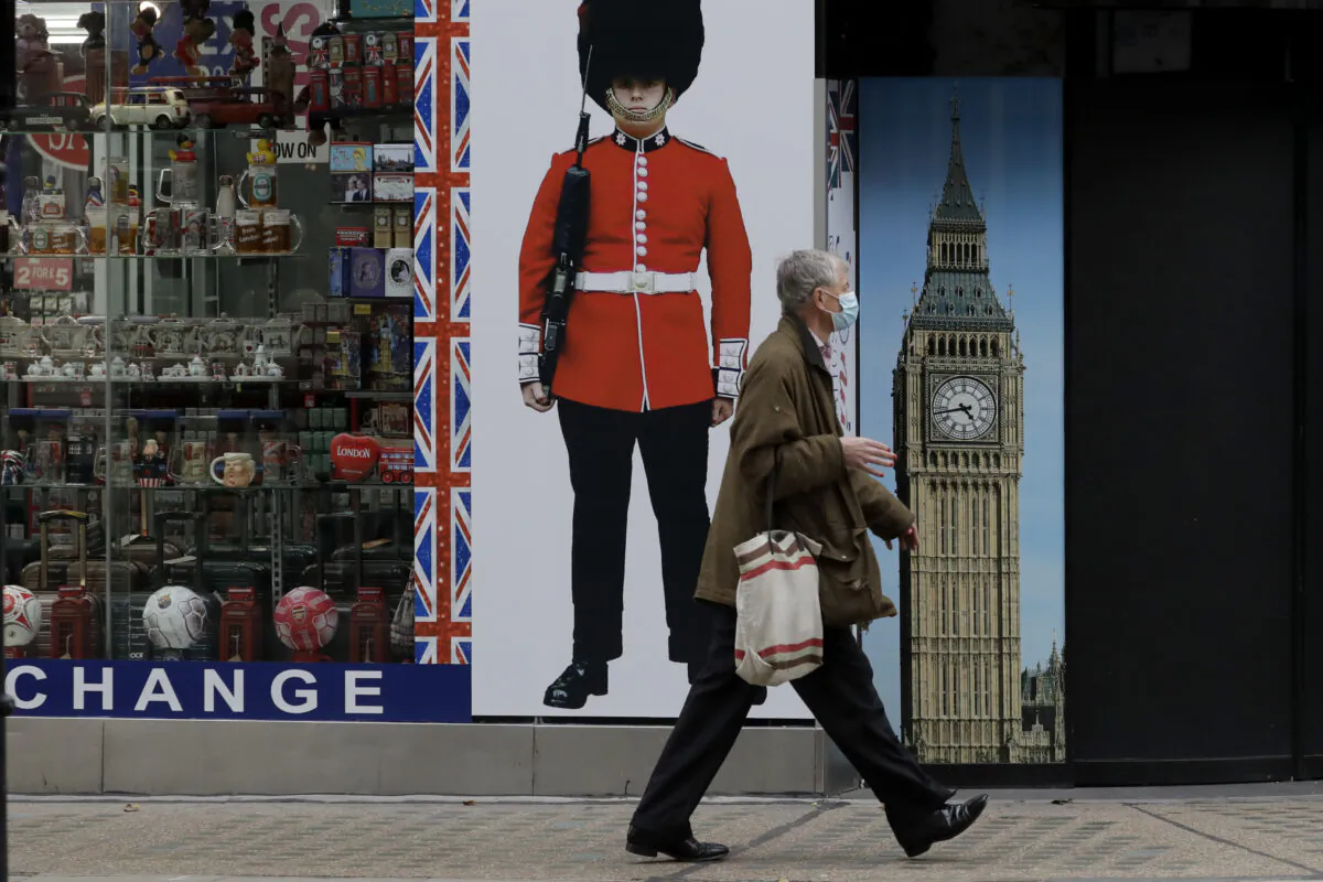 A person wearing a face mask walks past a temporarily closed souvenir store on Oxford Street, during England's second CCP virus lockdown in London, on Nov. 23, 2020. (AP Photo/Matt Dunham)