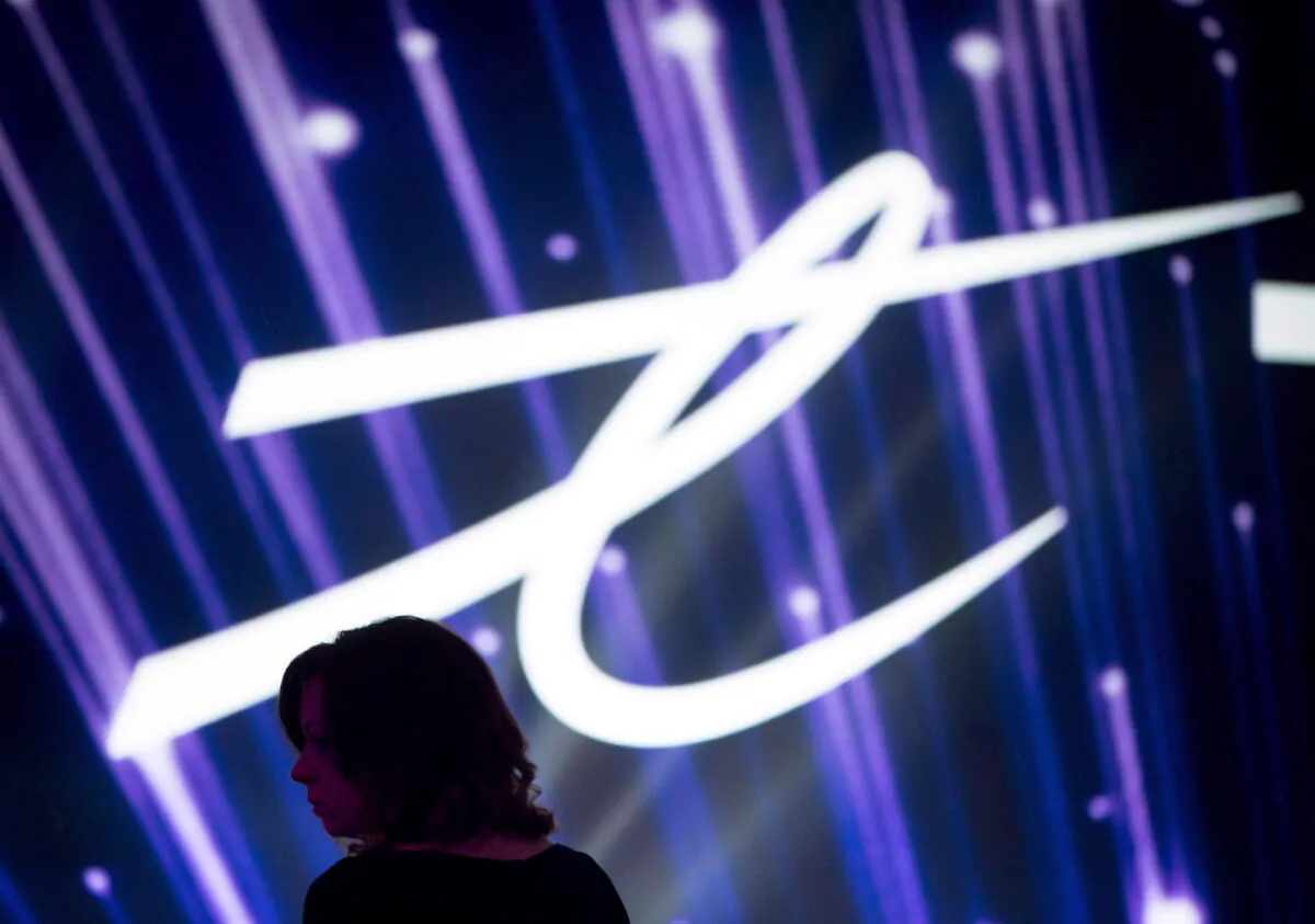 A woman is silhouetted as the Telus Corp. logo is displayed on a screen during a company event in Vancouver, Canada on Oct. 2, 2015. (Darryl Dyck/The Canadian Press)