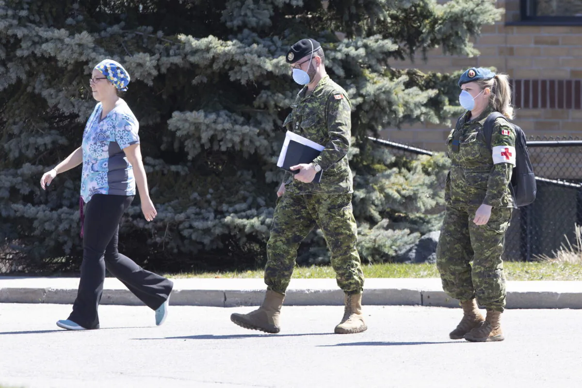 A staff member escorts members of the Canadian Armed Forces in to a long term care home, in Pickering, Ont., on April 25, 2020. (Chris Young/The Canadian Press)