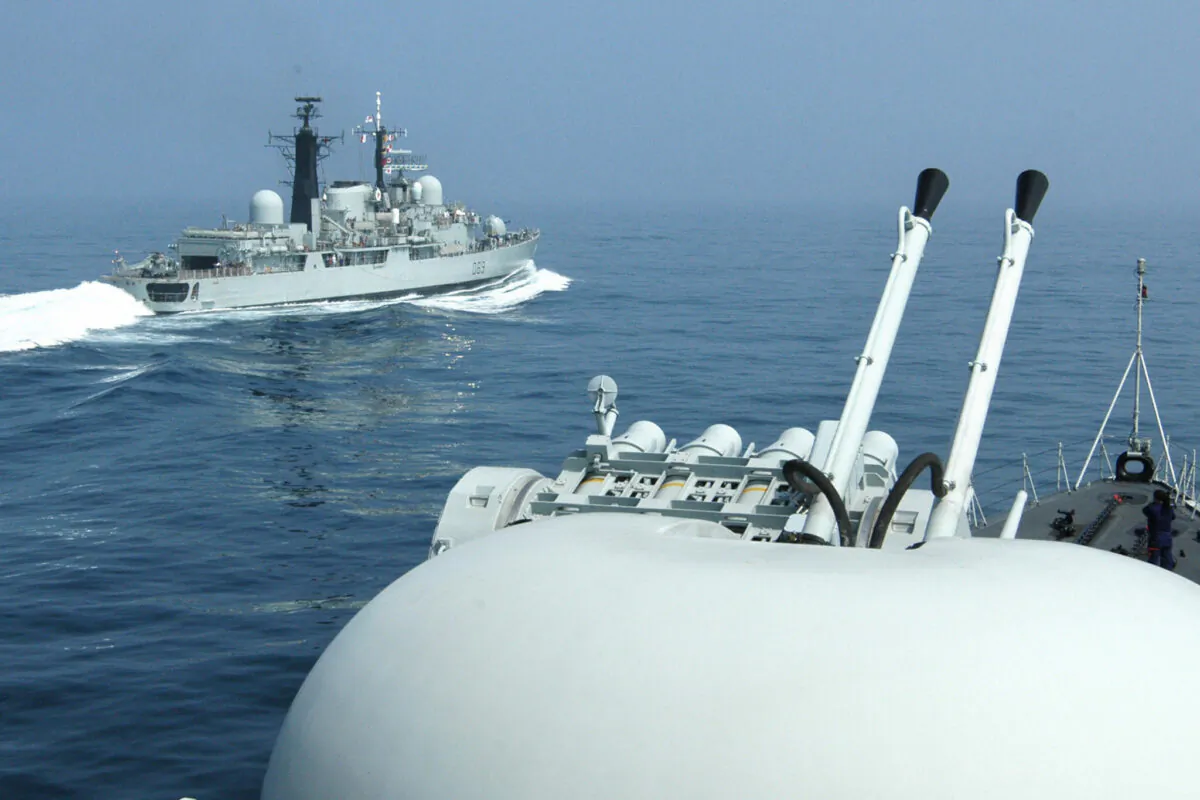British Royal Navy guided missile destroyer HMS Exeter (L) passes a Chinese naval vessel off the eastern port city of Qingdao, China, on June 20, 2004. (STR/AFP via Getty Images)