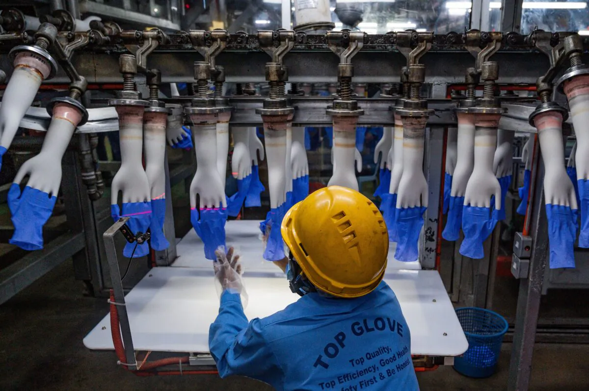A worker inspects disposable gloves at the Top Glove factory production line in Shah Alam on the outskirts of Kuala Lumpur, Malaysia, on Aug. 26, 2020.
(Mohd Rasfan/AFP via Getty Images)
