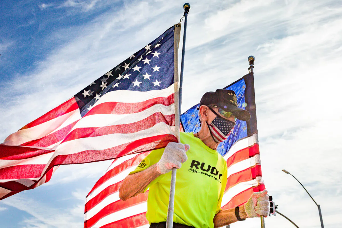 Robert Kohler, 89, runs the virtual 2020 Turkey Trot holding two large American flags in Dana Point, Calif., on Nov. 21, 2020. (John Fredricks/The Epoch Times)
