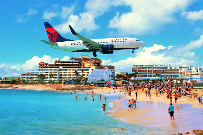 An airplane flies over Maho Beach en route to Princess Juliana International Airport. (Gemma Fletcher/Shutterstock)