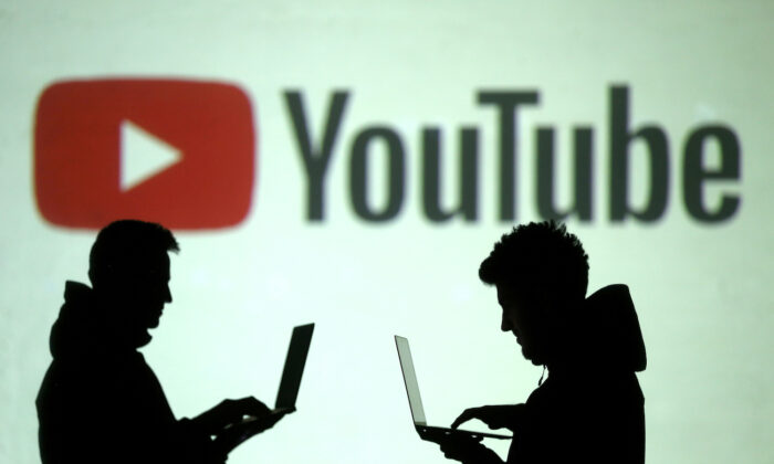 Silhouettes of mobile device users are seen next to a screen projection of YouTube's logo in this picture illustration taken March 28, 2018. (Dado Ruvic/Illustration/Reuters)
