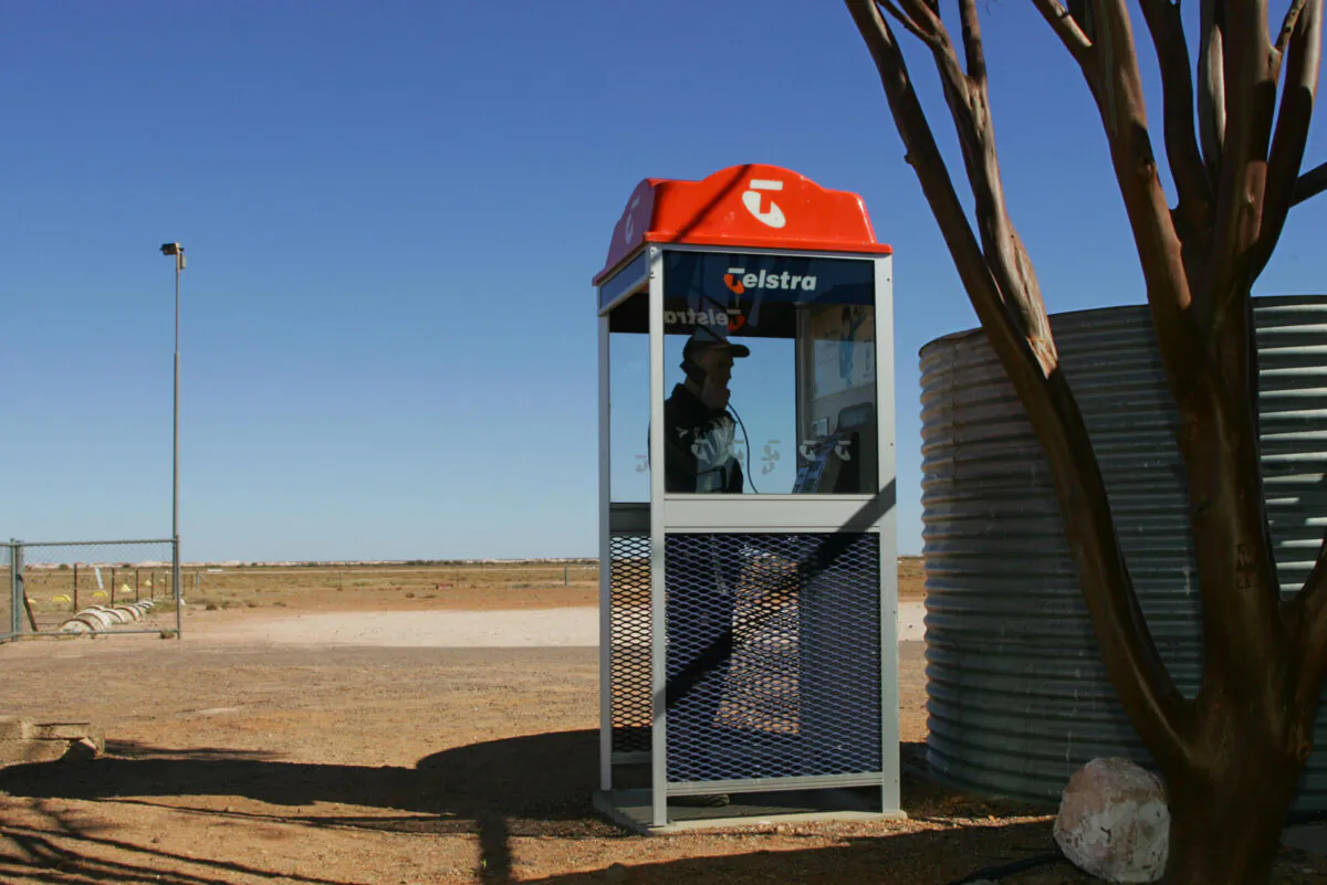 Tim Nagy makes a call from a Telstra public phone booth near the outback opal mining community of Coober Pedy, Australia, on July 5, 2005. (Torsten Blackwood/AFP via Getty Images)
